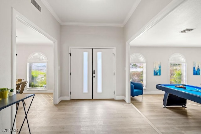 foyer entrance with ornamental molding, a healthy amount of sunlight, visible vents, and light wood-style floors