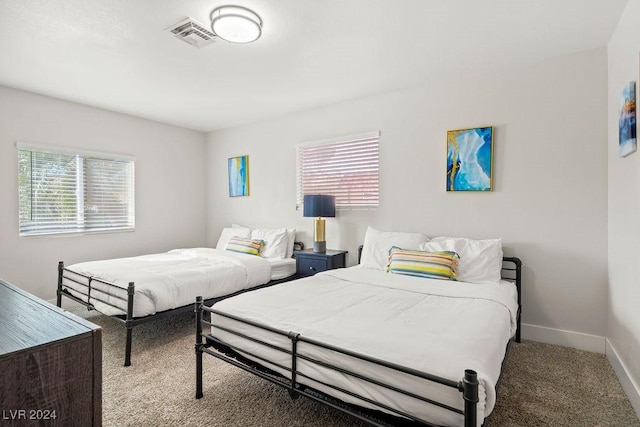 bedroom featuring light carpet, multiple windows, visible vents, and baseboards