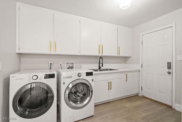 laundry room with light wood-type flooring, a sink, cabinet space, and washer and dryer