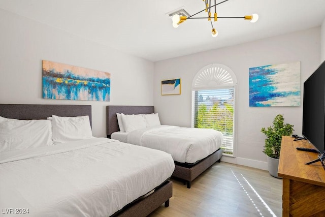 bedroom with a chandelier, light wood-style flooring, and baseboards