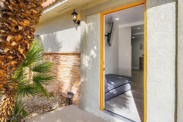 entrance to property with visible vents and stucco siding