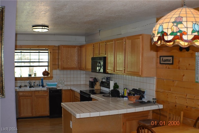 kitchen with decorative backsplash, tile counters, black appliances, and kitchen peninsula