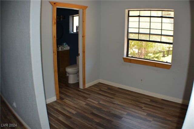 unfurnished bedroom with dark wood-type flooring and ensuite bathroom