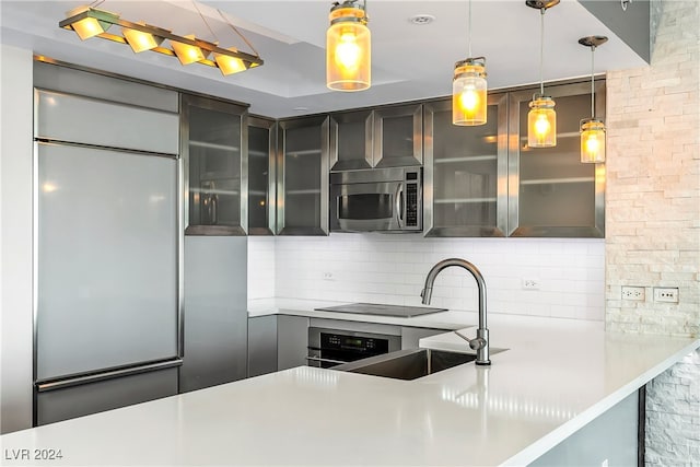 kitchen with stovetop, built in refrigerator, sink, decorative backsplash, and decorative light fixtures