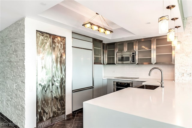 kitchen with appliances with stainless steel finishes, sink, pendant lighting, a tray ceiling, and dark tile patterned flooring