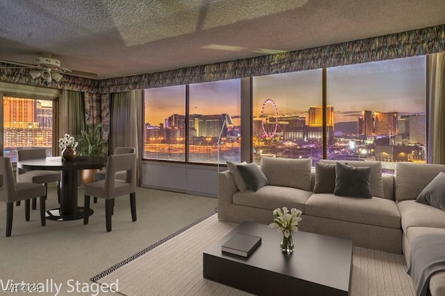 living room featuring ceiling fan, carpet floors, and a textured ceiling