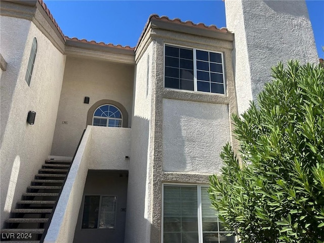 exterior space featuring a tile roof and stucco siding