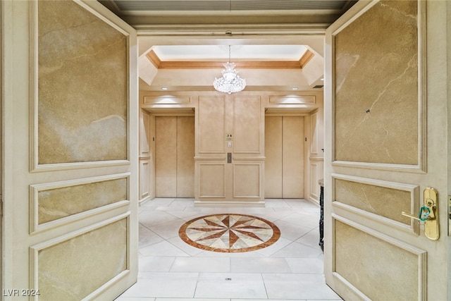 foyer entrance featuring light tile patterned floors, ornamental molding, a raised ceiling, and elevator