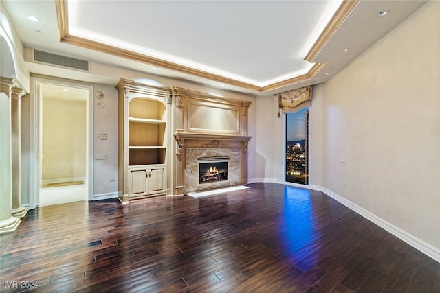 unfurnished living room with a high end fireplace, a raised ceiling, built in features, and dark hardwood / wood-style floors