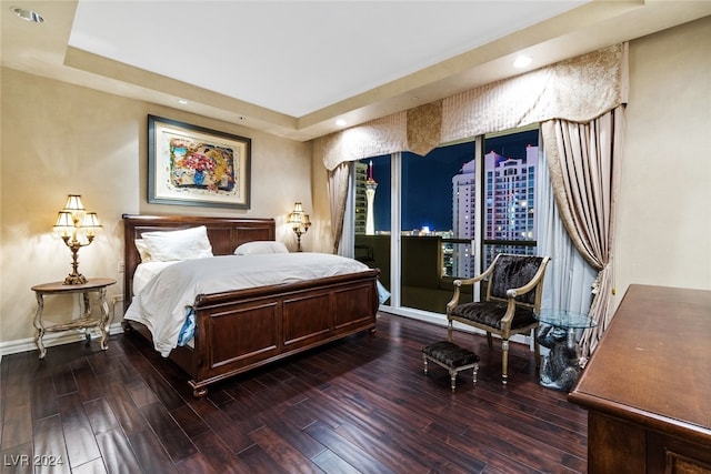 bedroom featuring a tray ceiling, dark hardwood / wood-style flooring, and access to outside