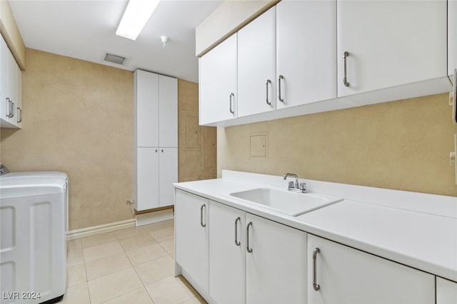 clothes washing area featuring washer / dryer, light tile patterned floors, cabinets, and sink