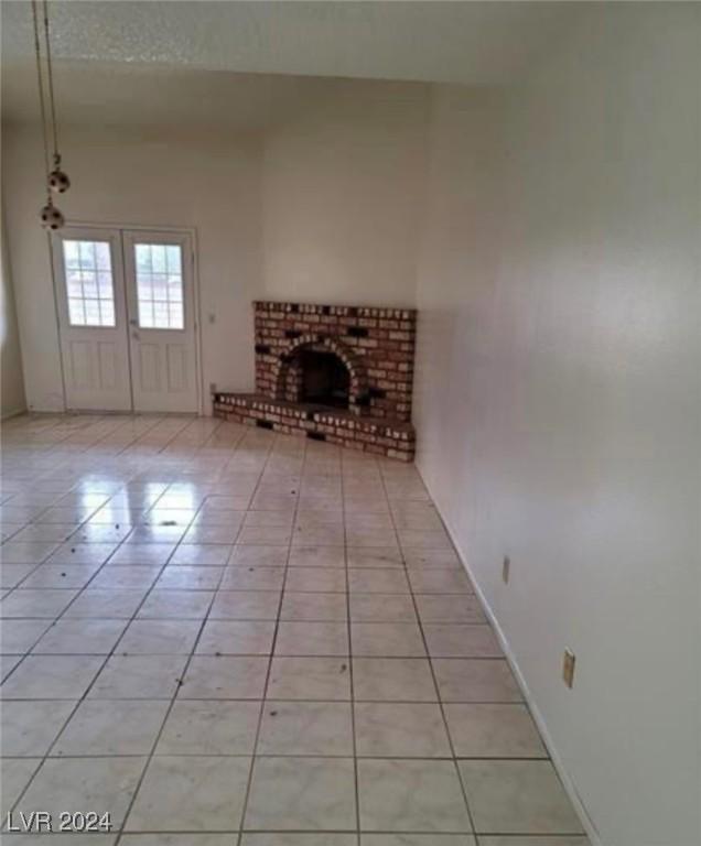 unfurnished living room with light tile patterned flooring and a brick fireplace