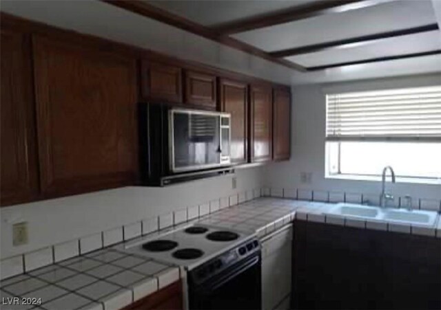 kitchen featuring tile counters, stove, and sink