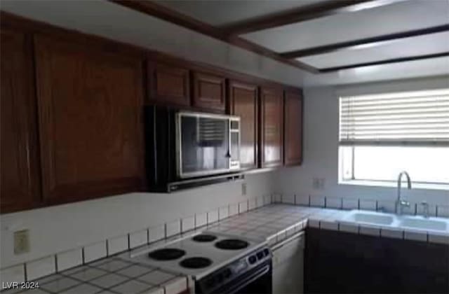 kitchen with stove, sink, and tile countertops