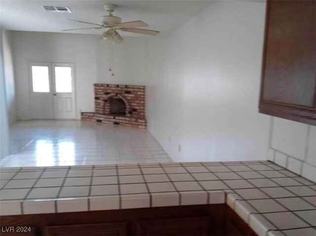 unfurnished living room featuring a brick fireplace and ceiling fan