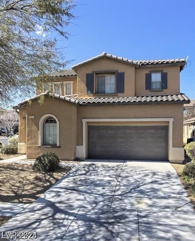 view of front facade featuring a garage, driveway, a tile roof, and stucco siding