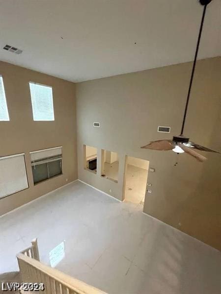 unfurnished living room featuring a towering ceiling, visible vents, and a ceiling fan