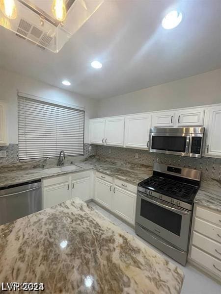 kitchen featuring light stone counters, appliances with stainless steel finishes, backsplash, and a sink