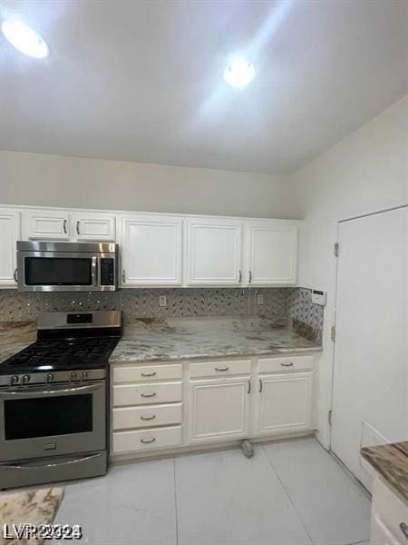 kitchen with stainless steel appliances, backsplash, and white cabinets