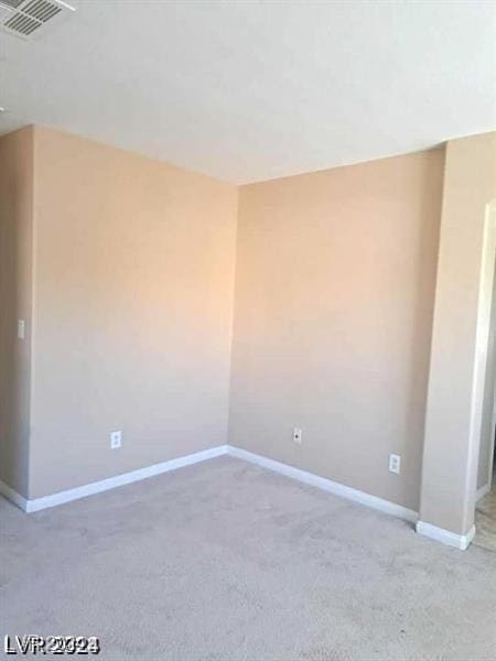 spare room with carpet floors, visible vents, and baseboards