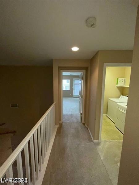 hall with independent washer and dryer and an upstairs landing