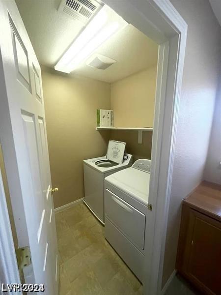 washroom featuring laundry area, visible vents, baseboards, and separate washer and dryer