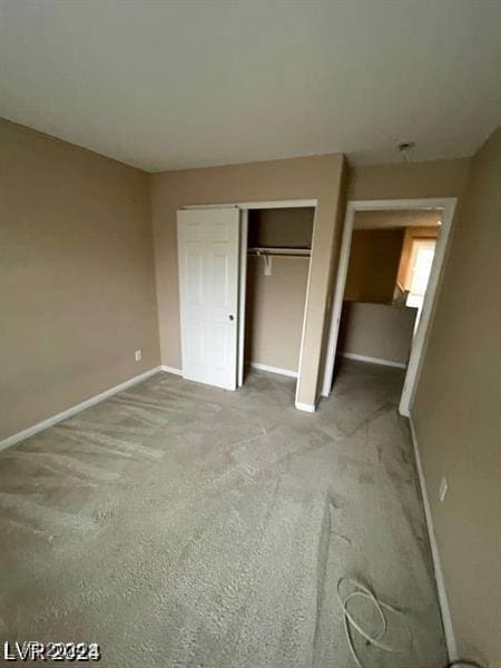 unfurnished bedroom featuring a closet, light colored carpet, and baseboards