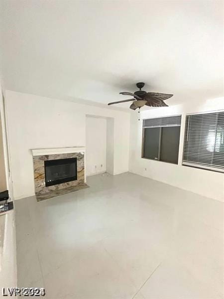 unfurnished living room with concrete floors, ceiling fan, and a fireplace