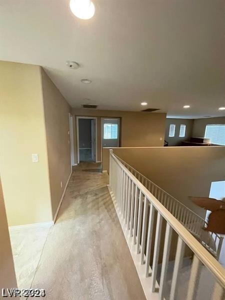 corridor with light wood-style floors, visible vents, baseboards, and recessed lighting