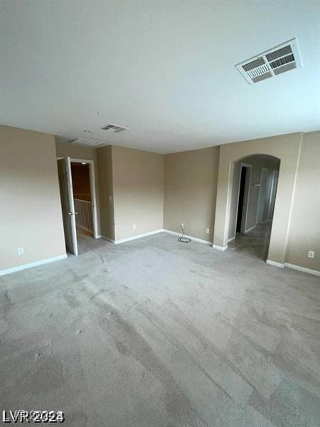 unfurnished room featuring arched walkways, visible vents, and baseboards