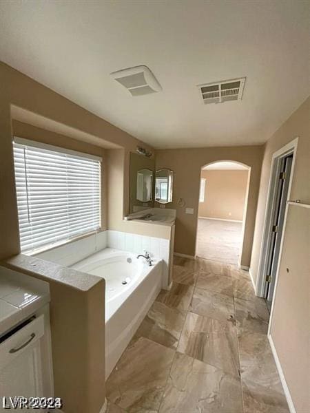 bathroom with a garden tub, vanity, visible vents, baseboards, and marble finish floor