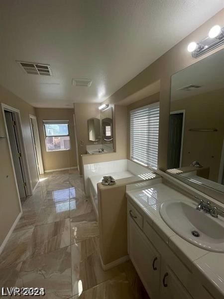 full bath with vanity, a garden tub, visible vents, and baseboards