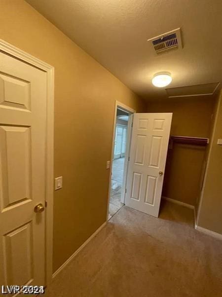 hall with light carpet, baseboards, and visible vents