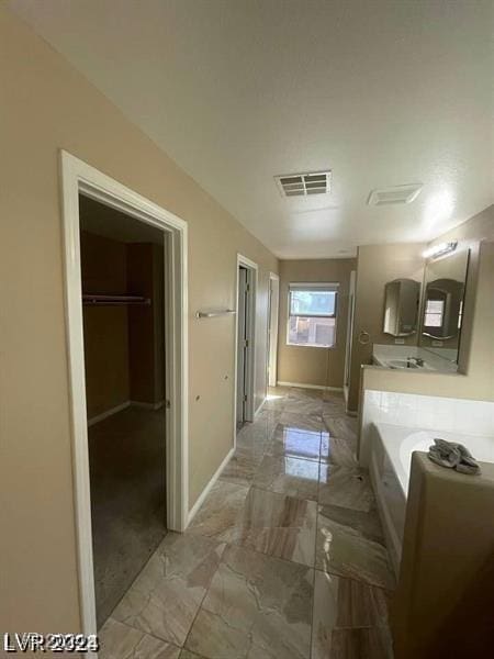 bathroom with marble finish floor, visible vents, baseboards, and a bath