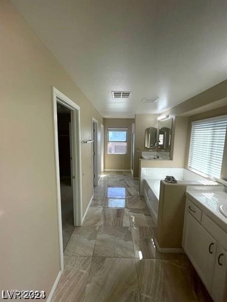 bathroom with baseboards, visible vents, marble finish floor, vanity, and a bath