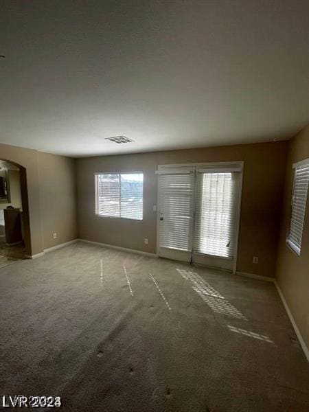 interior space with arched walkways, carpet floors, visible vents, and baseboards