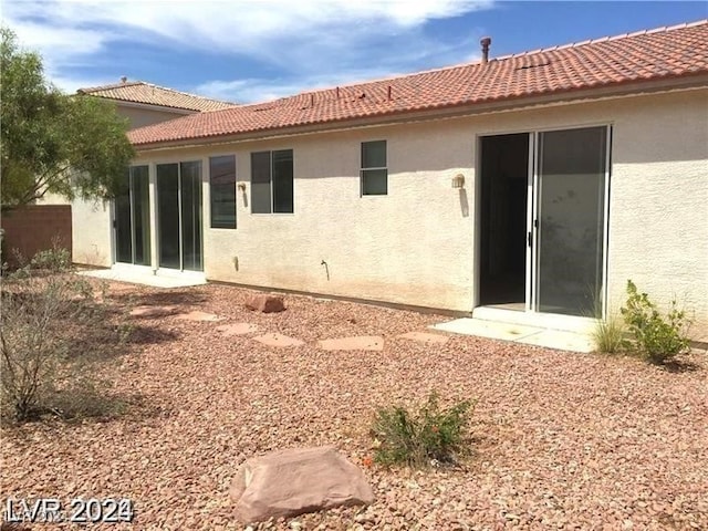 rear view of house with stucco siding and a tile roof