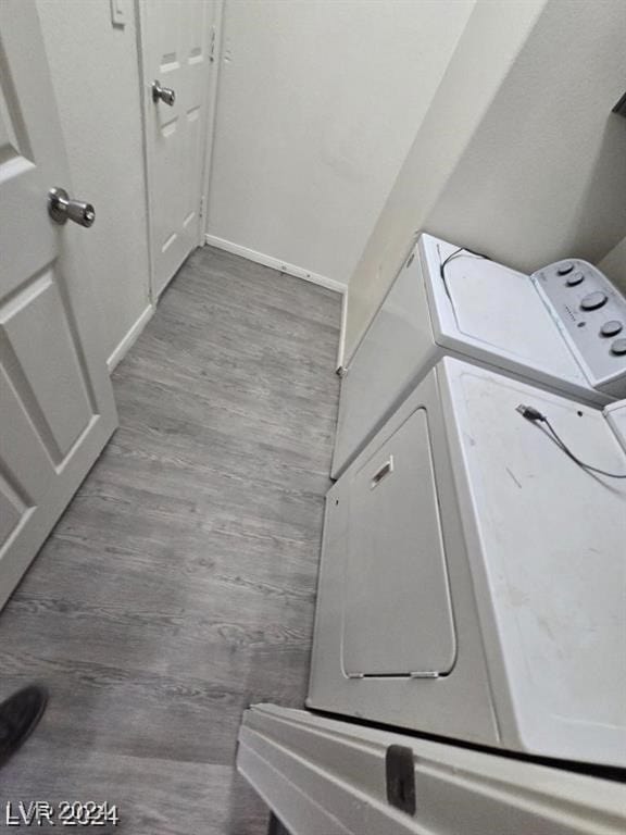 washroom with laundry area, wood finished floors, baseboards, and washing machine and clothes dryer