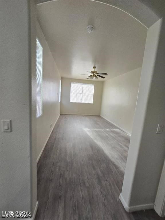 empty room featuring baseboards, wood finished floors, and a ceiling fan