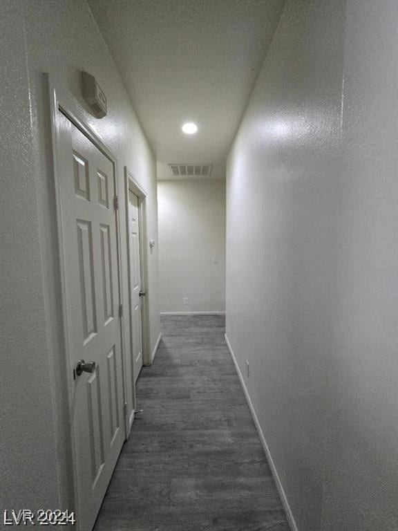 corridor with visible vents, baseboards, and dark wood-style flooring