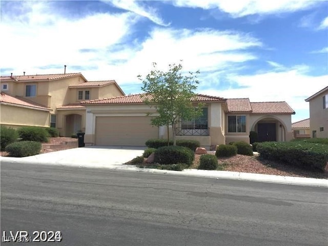 mediterranean / spanish-style home with concrete driveway, an attached garage, a tile roof, and stucco siding