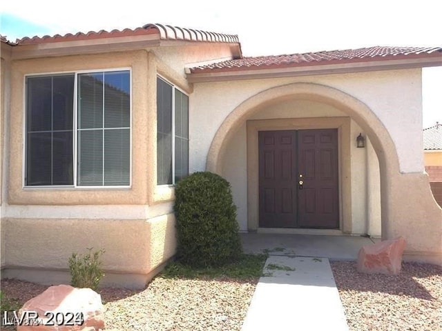 entrance to property with stucco siding and a tiled roof