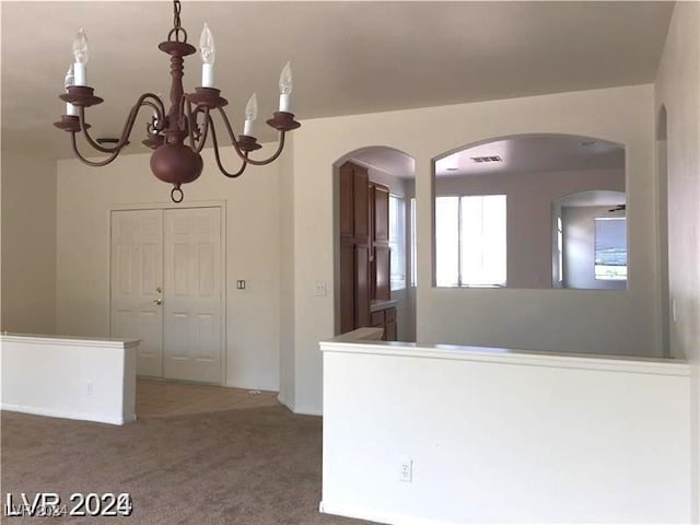 interior space with an inviting chandelier, visible vents, and carpet floors