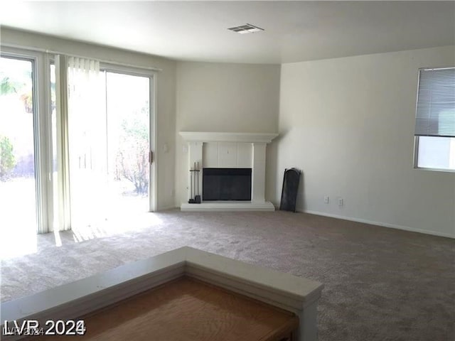 unfurnished living room with visible vents, a fireplace, baseboards, and carpet floors