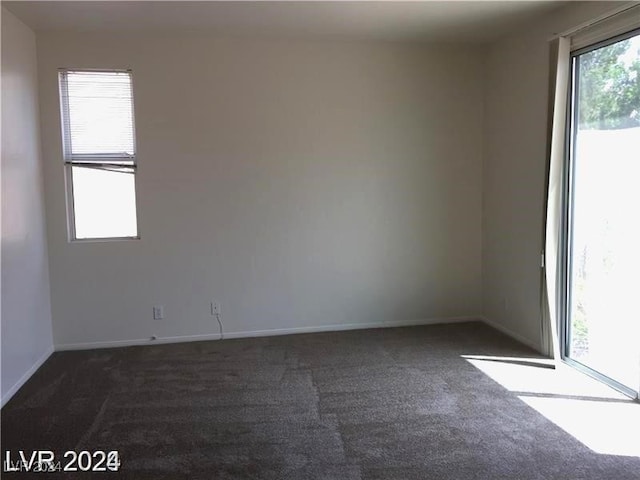 unfurnished room featuring baseboards and dark colored carpet