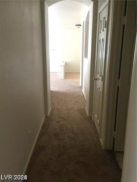 hallway featuring arched walkways and carpet