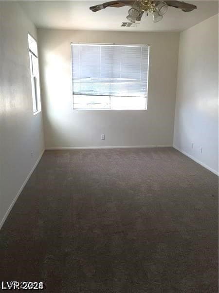 carpeted empty room with a ceiling fan, visible vents, and baseboards