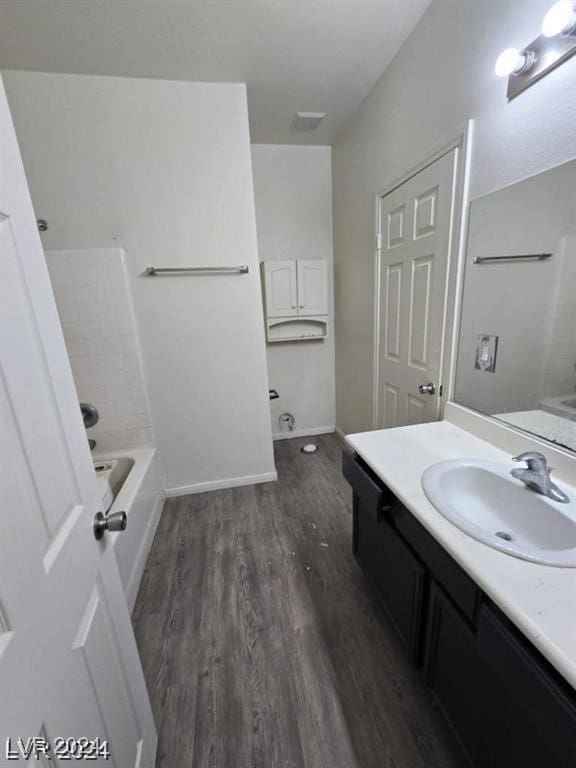 bathroom featuring vanity, shower / bathtub combination, baseboards, and wood finished floors