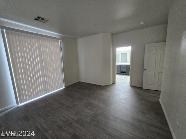 spare room with wood finished floors, visible vents, and baseboards