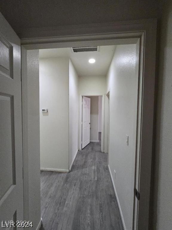 hall with dark wood-type flooring, baseboards, and visible vents